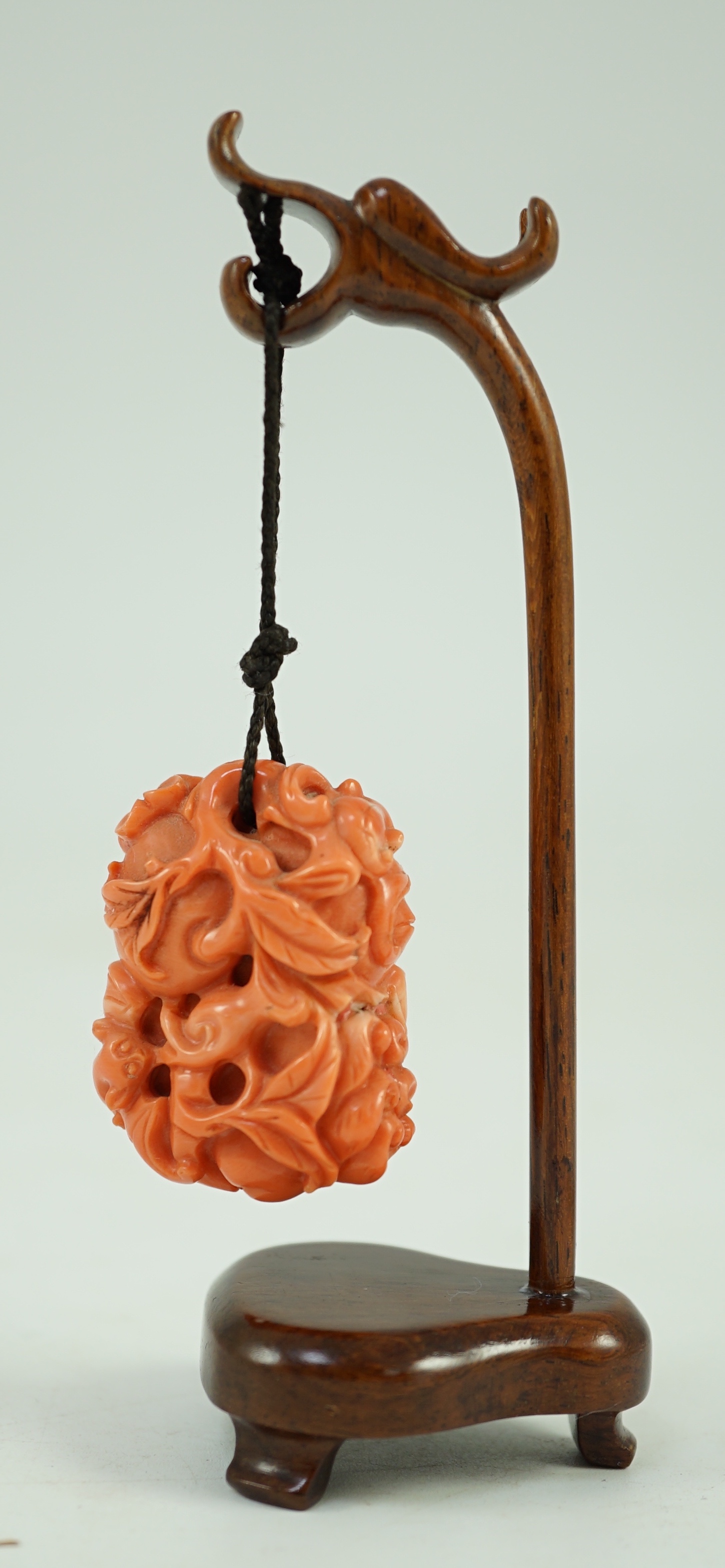 A good Chinese coral ‘fruit and bats’ pendant, 19th century, 3.7cm, later suspension stand